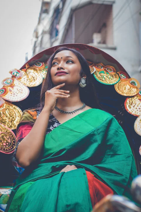 a woman in a green sari sitting on a colorfully decorated cart