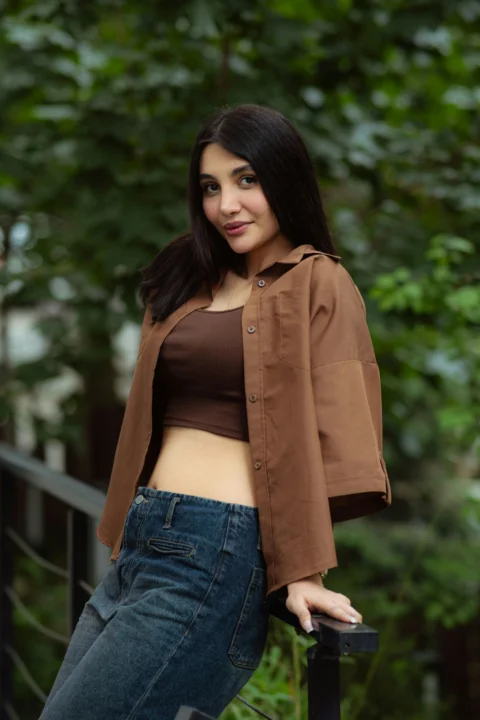 一名身穿棕色衬衫和牛仔裤的年轻女子在户外