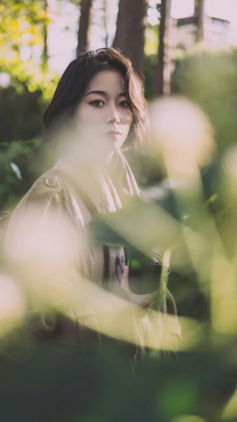 一位女子站在森林里,背景是树木