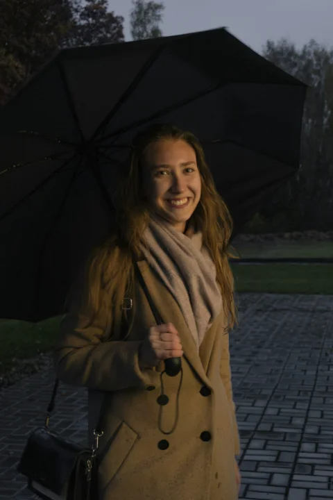 a woman holding a black umbrella on a sidewalk