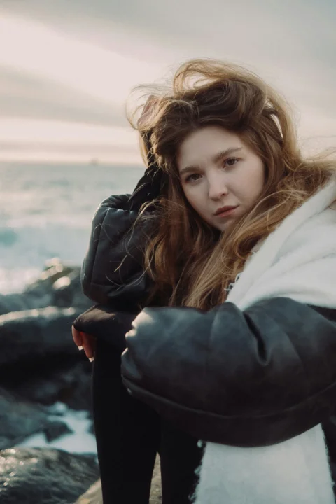 Young woman poses by the ocean