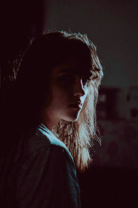 A woman with long hair standing in a dark room