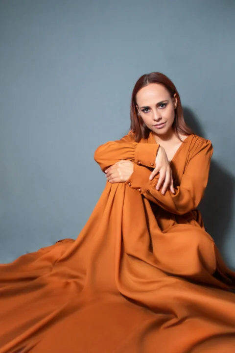 a woman in an orange dress posing for a picture