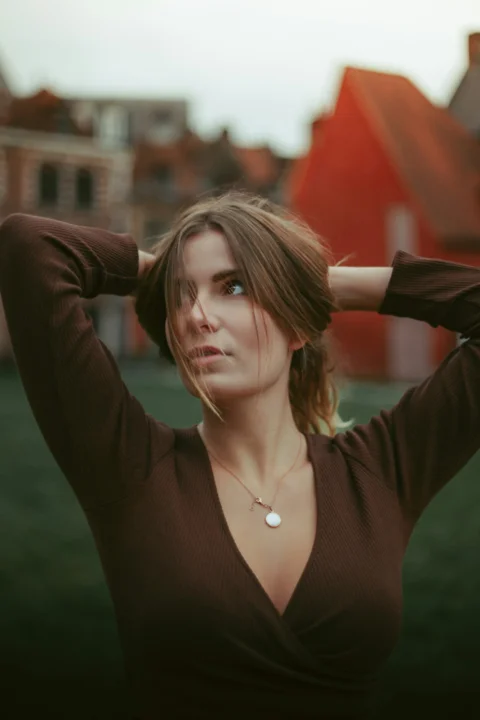 a woman in a brown shirt is holding her hair