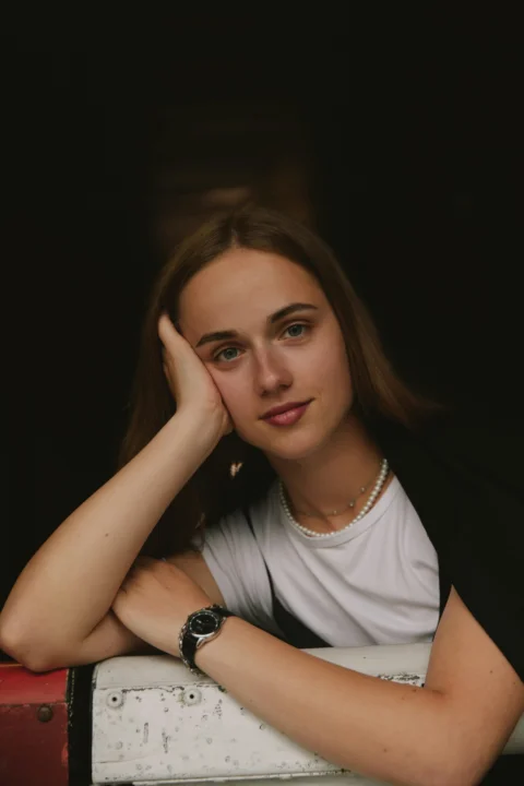 一只手扶着头靠在墙上的女子
