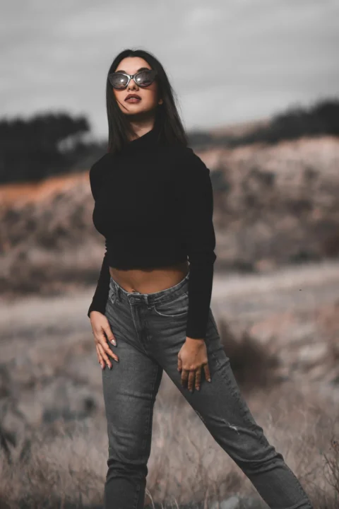 a woman standing in a field with her hands on her hips