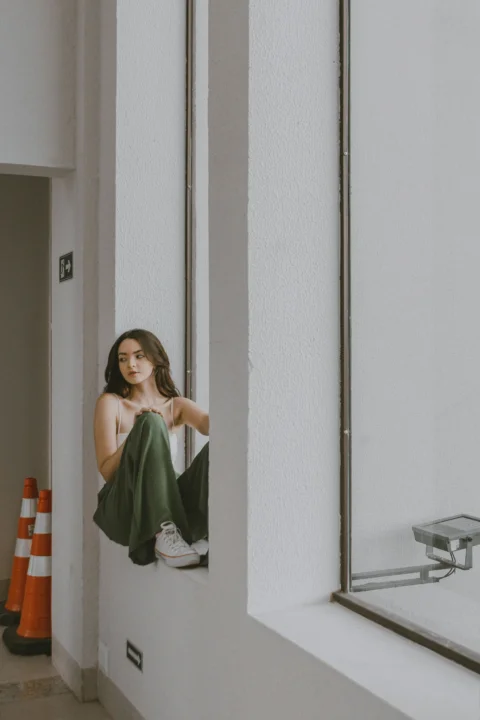 a woman sitting on a window sill looking out the window