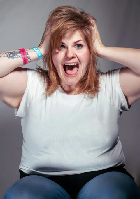 A woman sitting on a chair with her hands on her head