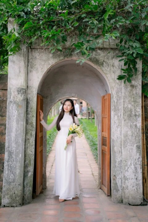 A woman in white stands at a stone archway