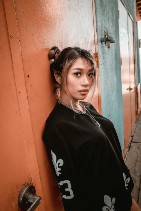 赤いドアのそばに立つ黒いジップアップジャケット姿の女性
