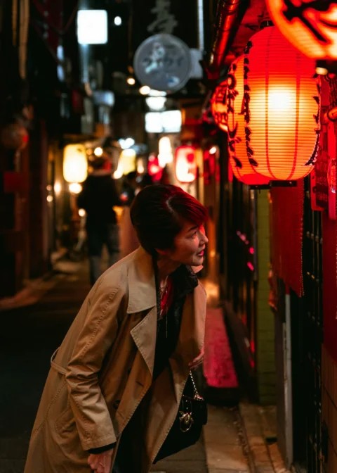 Woman looking at lanterns on a narrow street at night