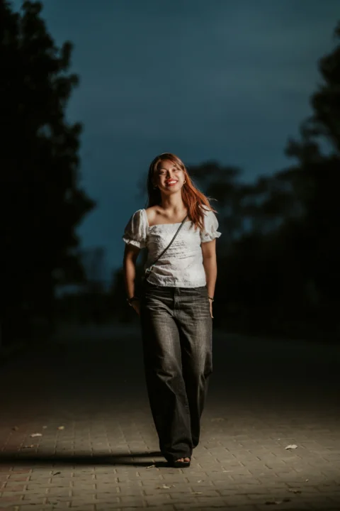 a woman walking down a sidewalk at night