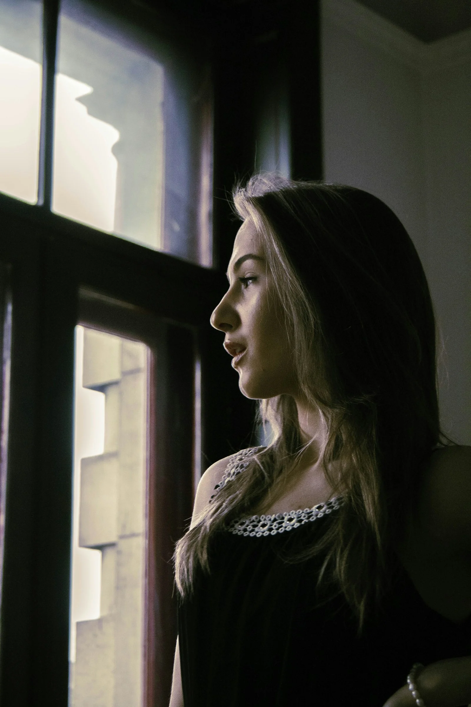 a woman standing in front of a window looking out
