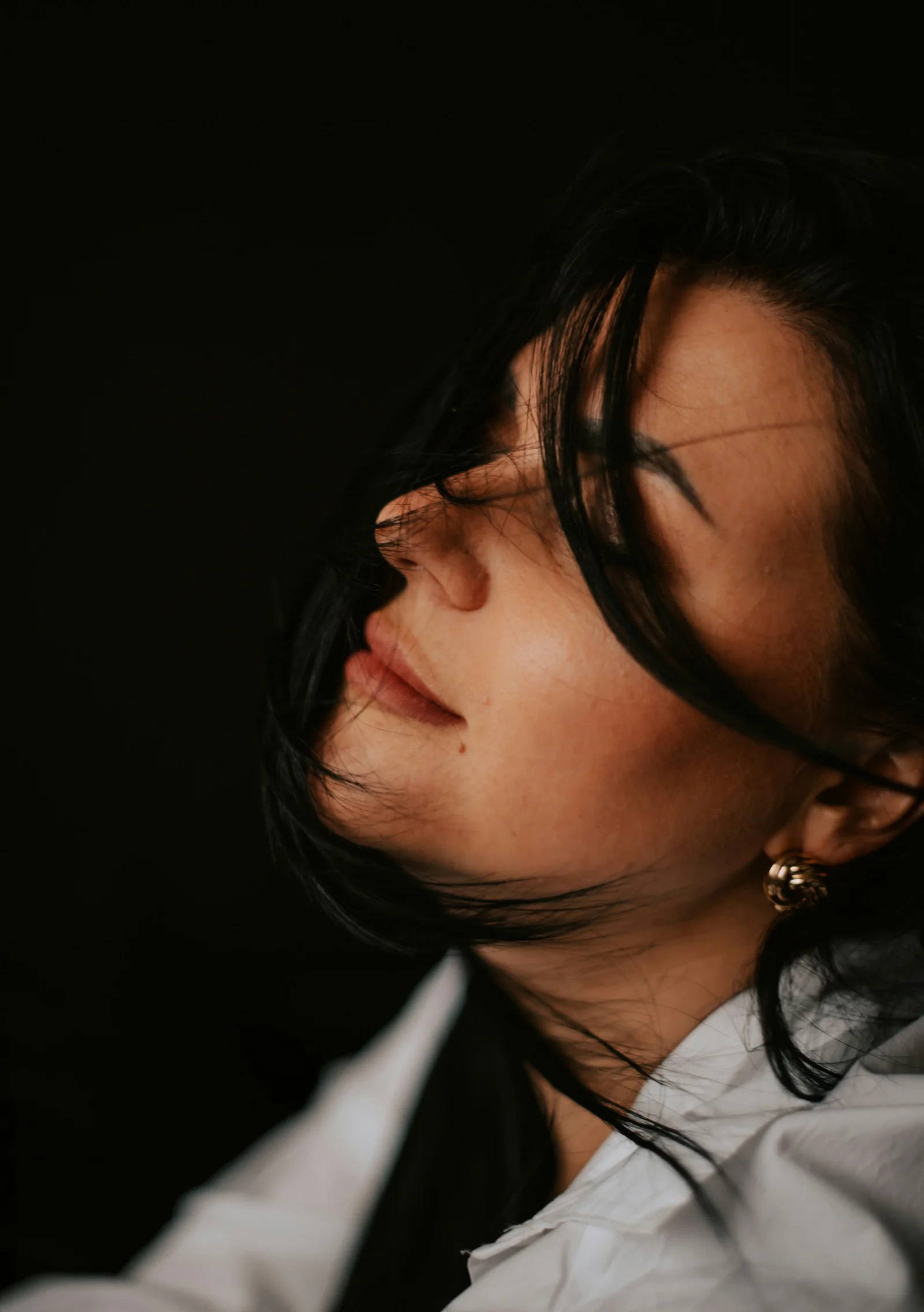 a woman in a white shirt and gold earrings