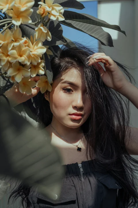 身穿黑白條紋襯衫、手持黃色花朵的女人