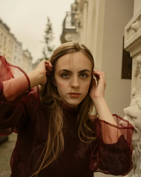 Woman with hands in hair poses in an urban setting