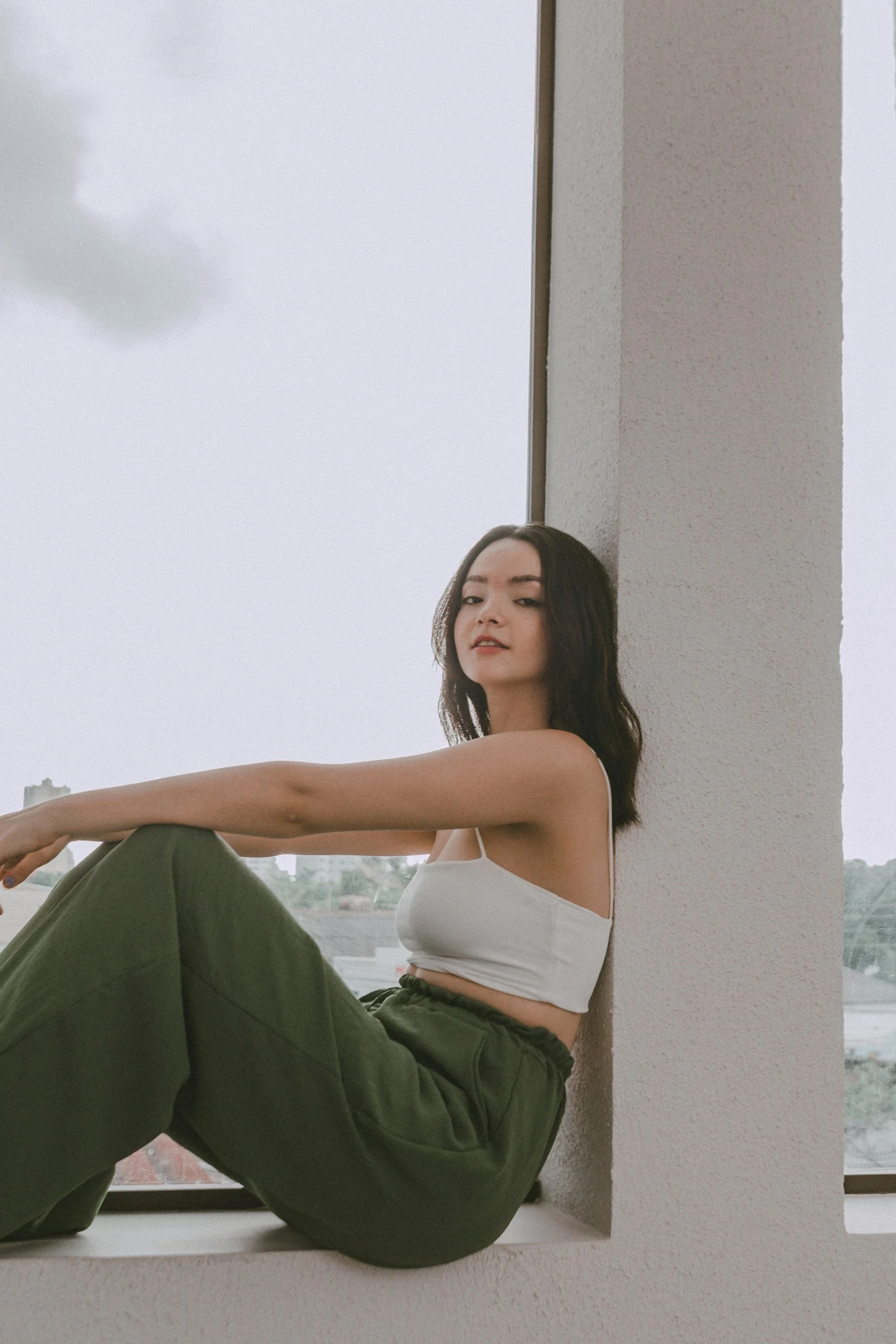 a woman sitting on a window sill with her legs crossed