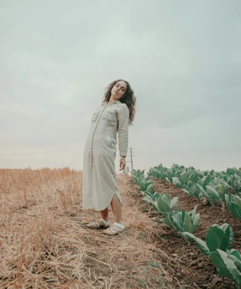 a woman in a white dress standing in a field