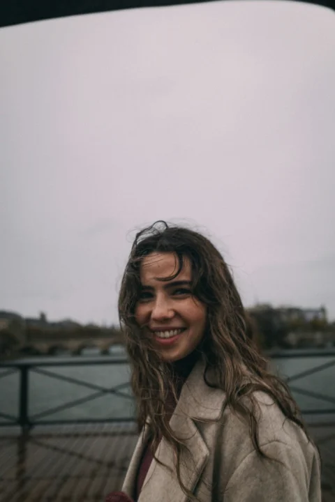 Smiling woman with wavy hair against a cloudy sky