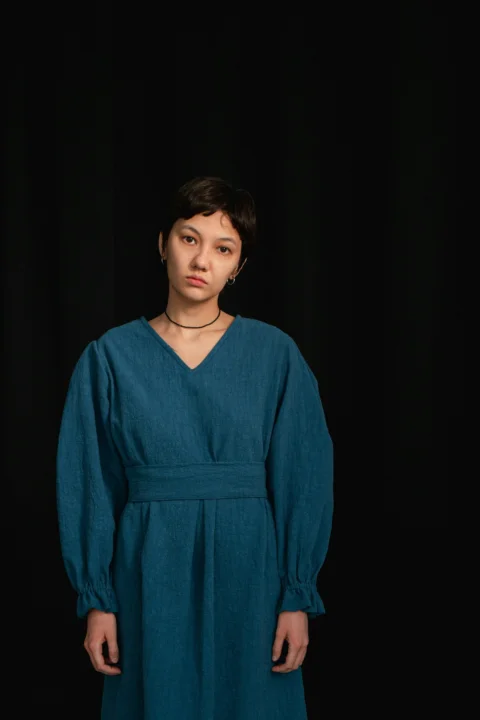 a woman in a blue dress standing in front of a black background