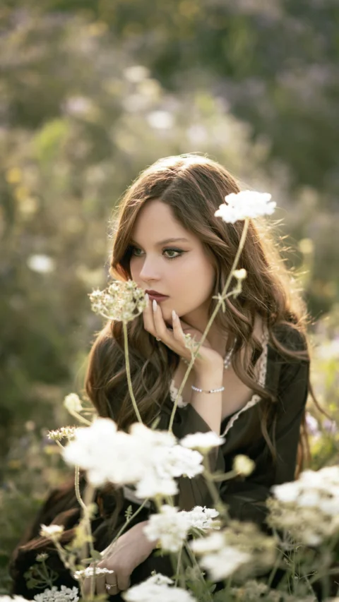 Young woman smelling flowers in a sunlit meadow