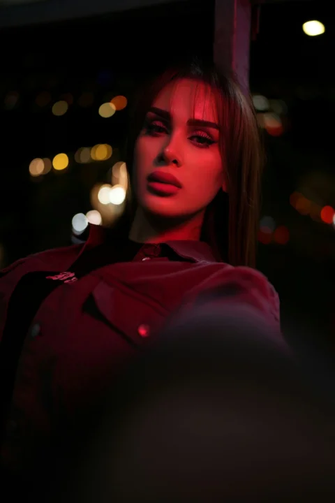 Woman illuminated by red light at night with bokeh lights