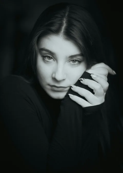 a black and white photo of a woman with her hands on her face