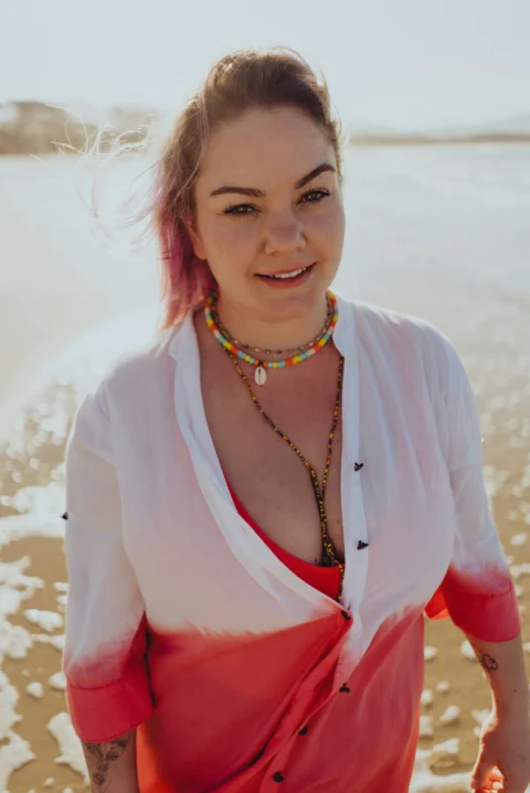 a woman with pink hair standing on a beach