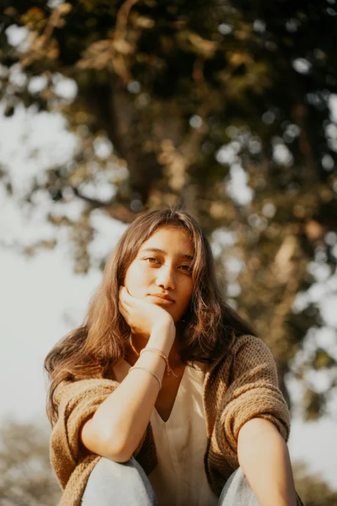A young woman sitting on top of a wooden bench