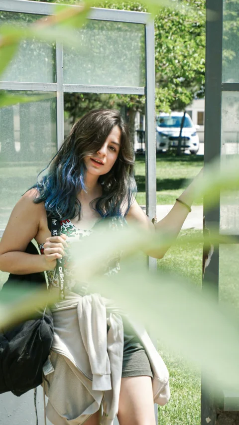a woman with blue hair sitting on a bench