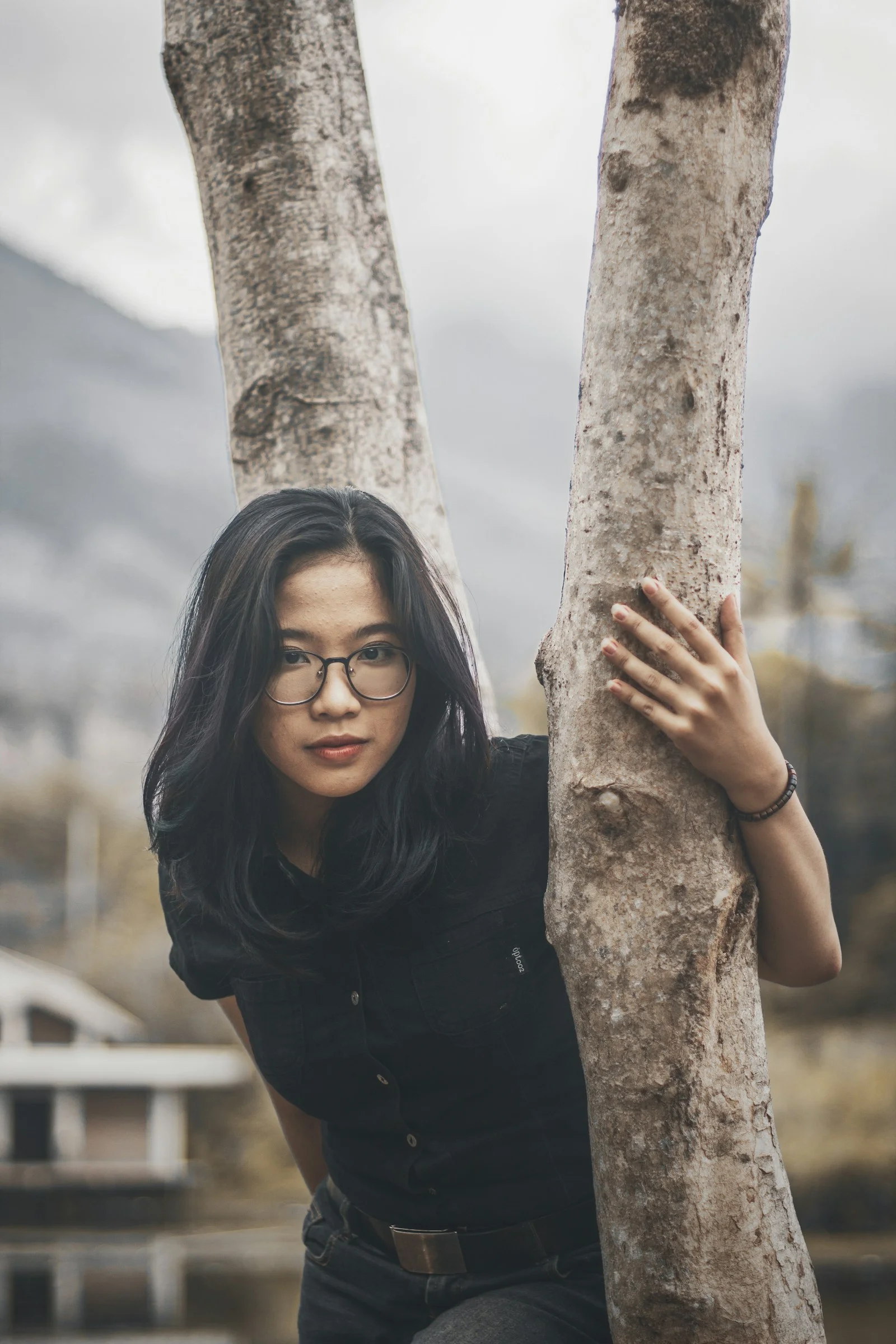 戴眼镜的女人倚靠在树上