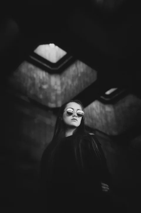 一个女人站在黑暗的房间里，闭着眼睛
