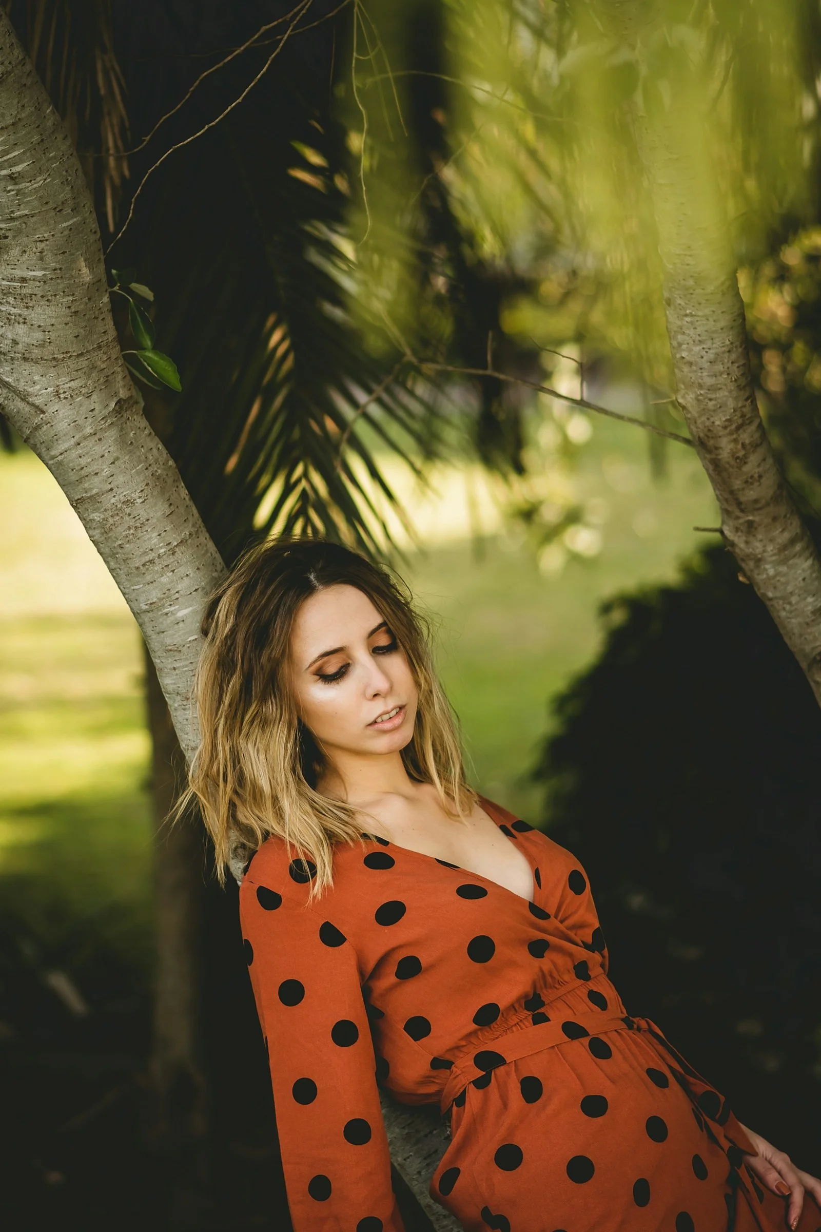 woman in red and black polka dot dress standing beside tree