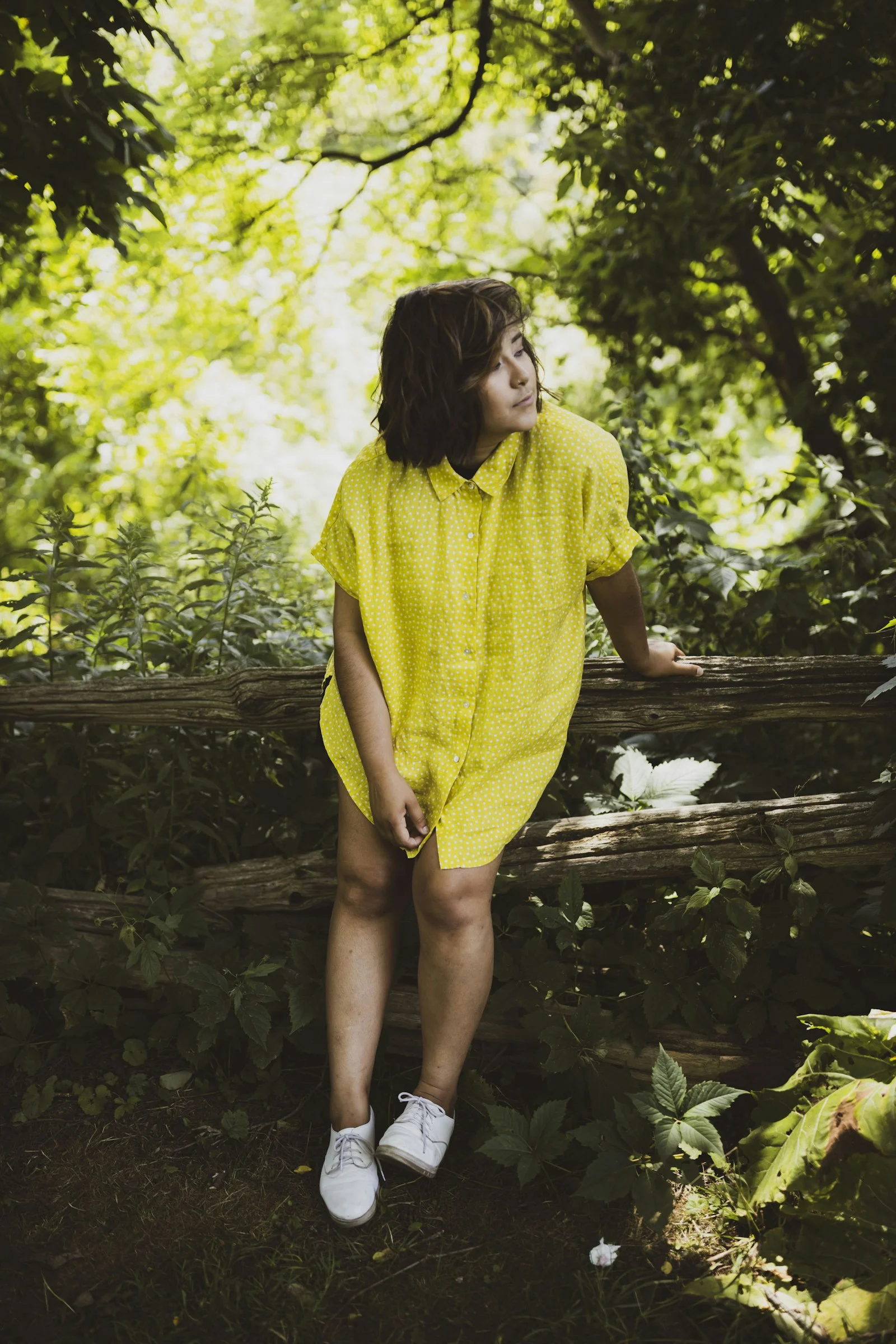 woman in yellow dress standing on brown wooden bridge