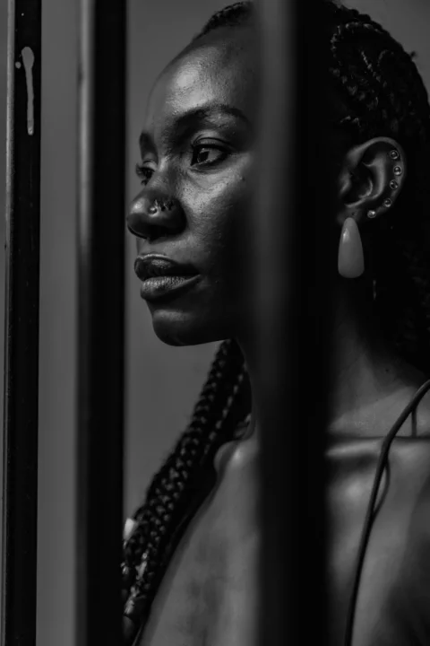 A woman with braids looking out of a window
