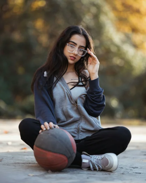 Young woman sits with basketball and glasses