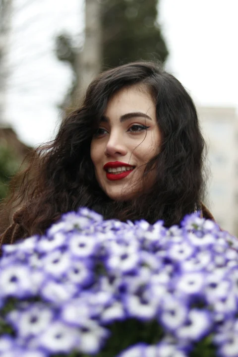 Woman with dark curly hair holding purple flowers