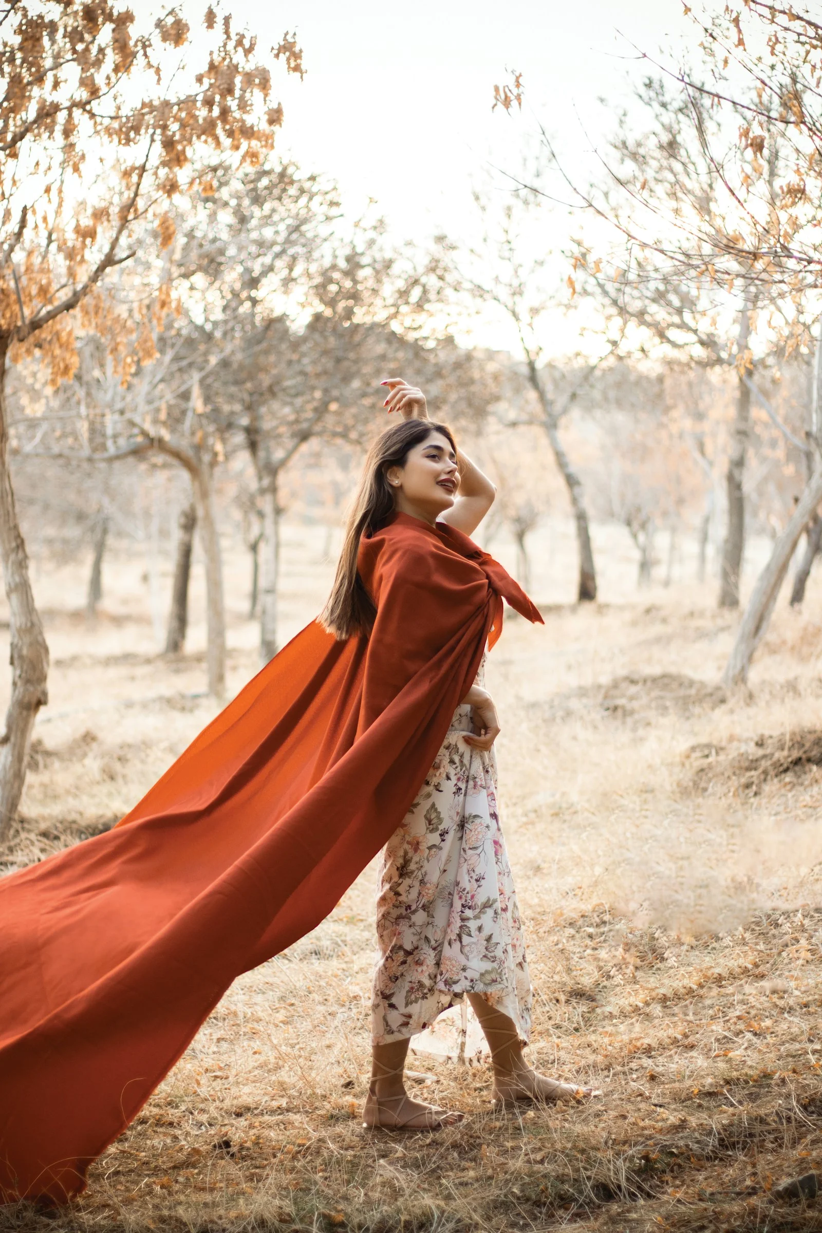 a woman in a red cape is standing in a field
