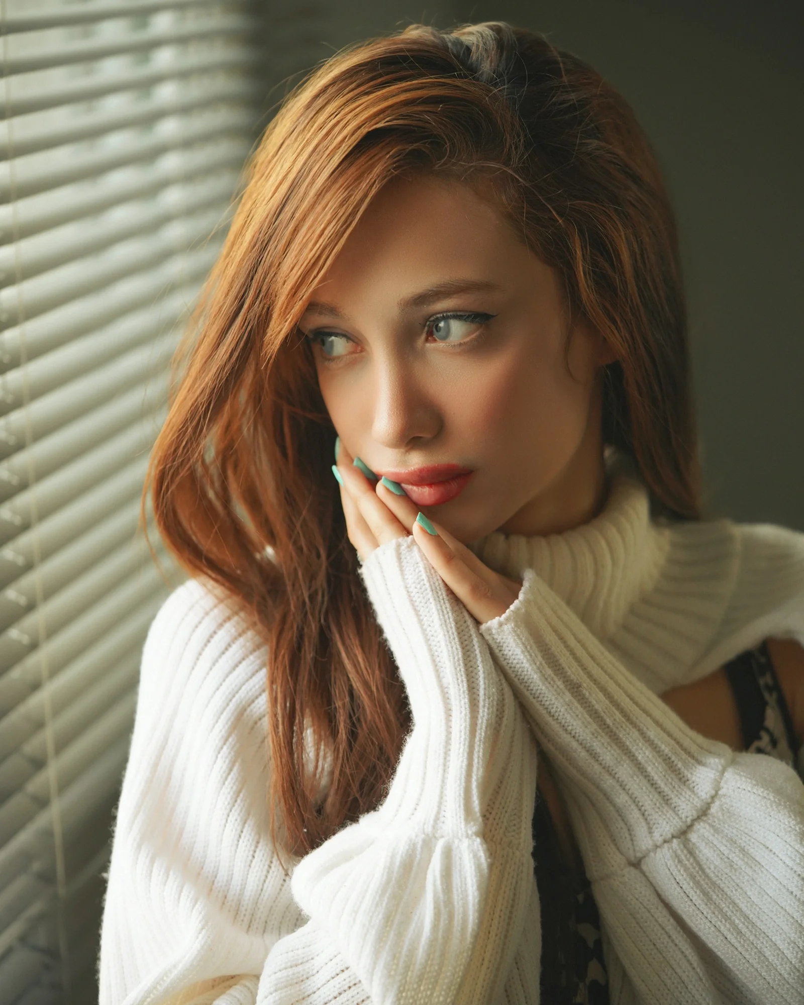 一名紅髮女子穿著白色毛衣