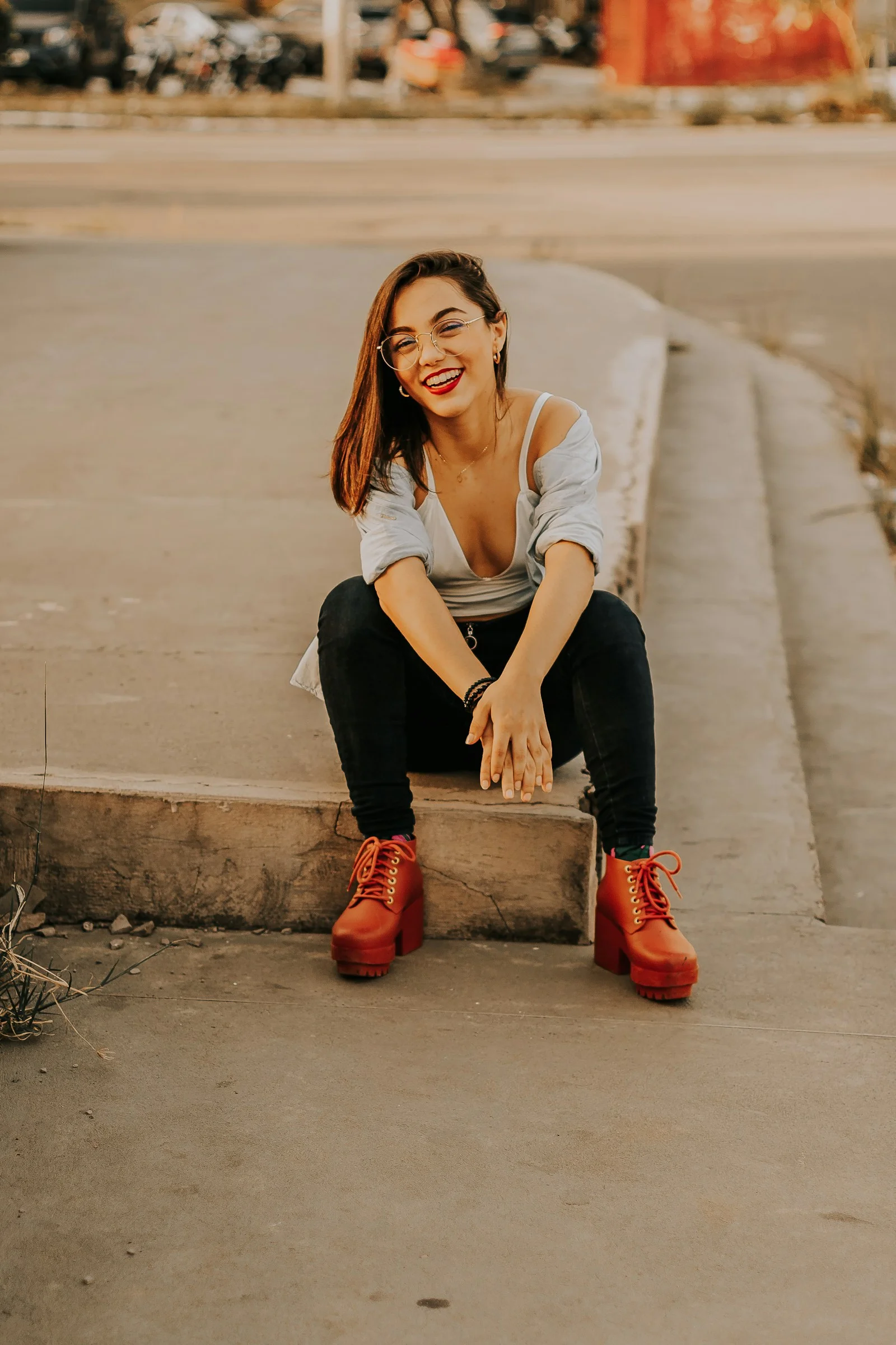 a woman sitting on a curb smiling at the camera