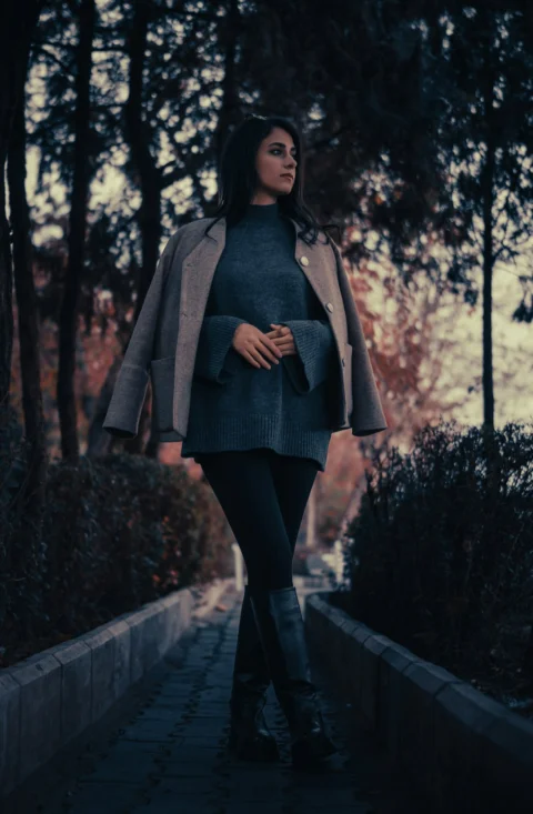 A woman walking down a sidewalk in a park