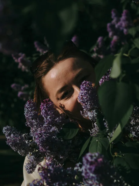 Woman peers through lilac flowers