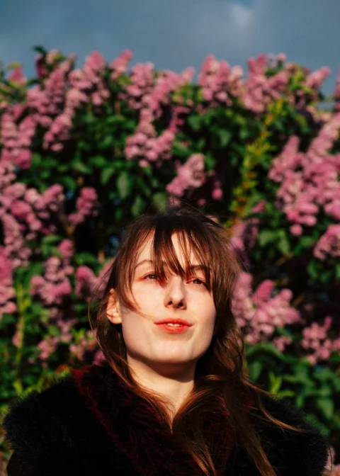 Young woman in front of blooming pink flowers