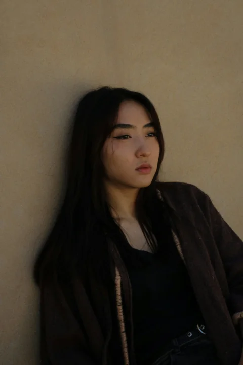 한 손을 허리에 대고 벽에 기댄 여성