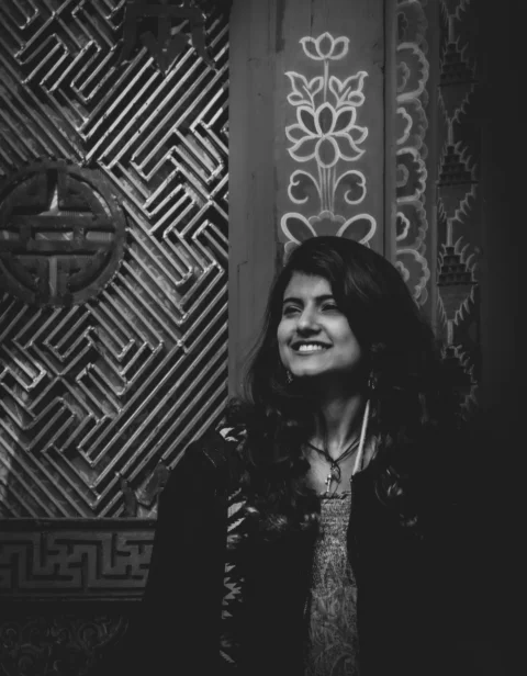 woman in black coat standing near brown wall