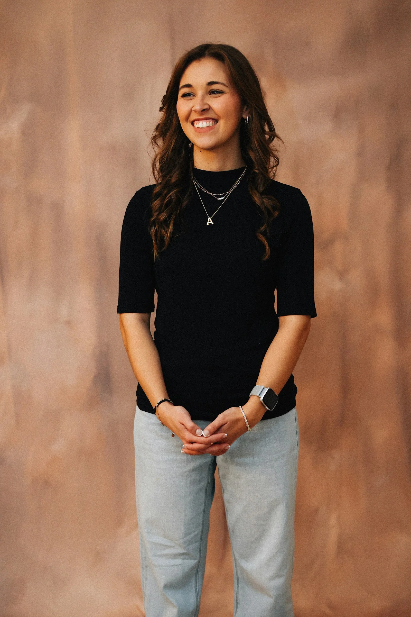 A woman smiles happily in front of a backdrop