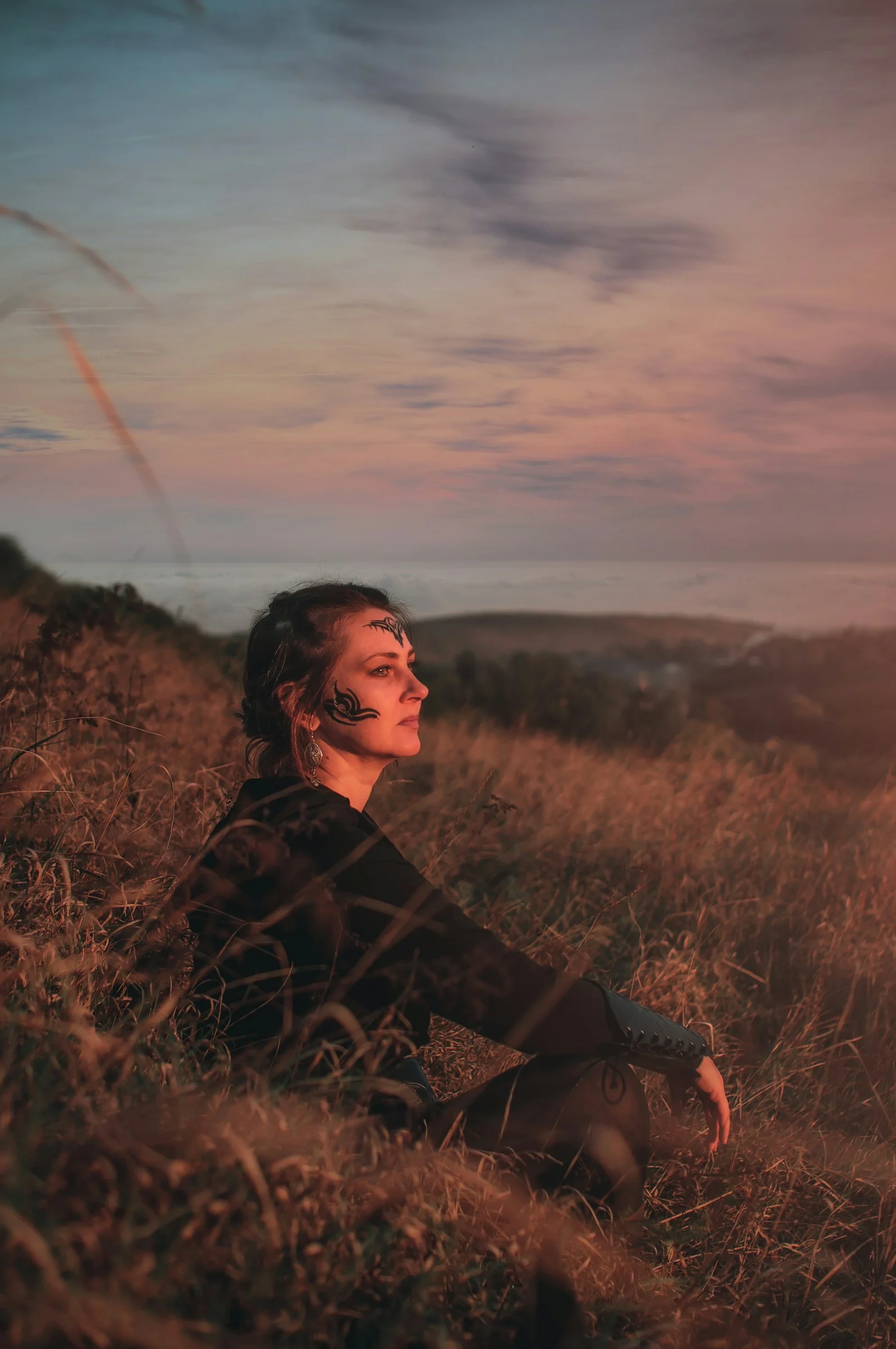 A woman sitting in a field at sunset