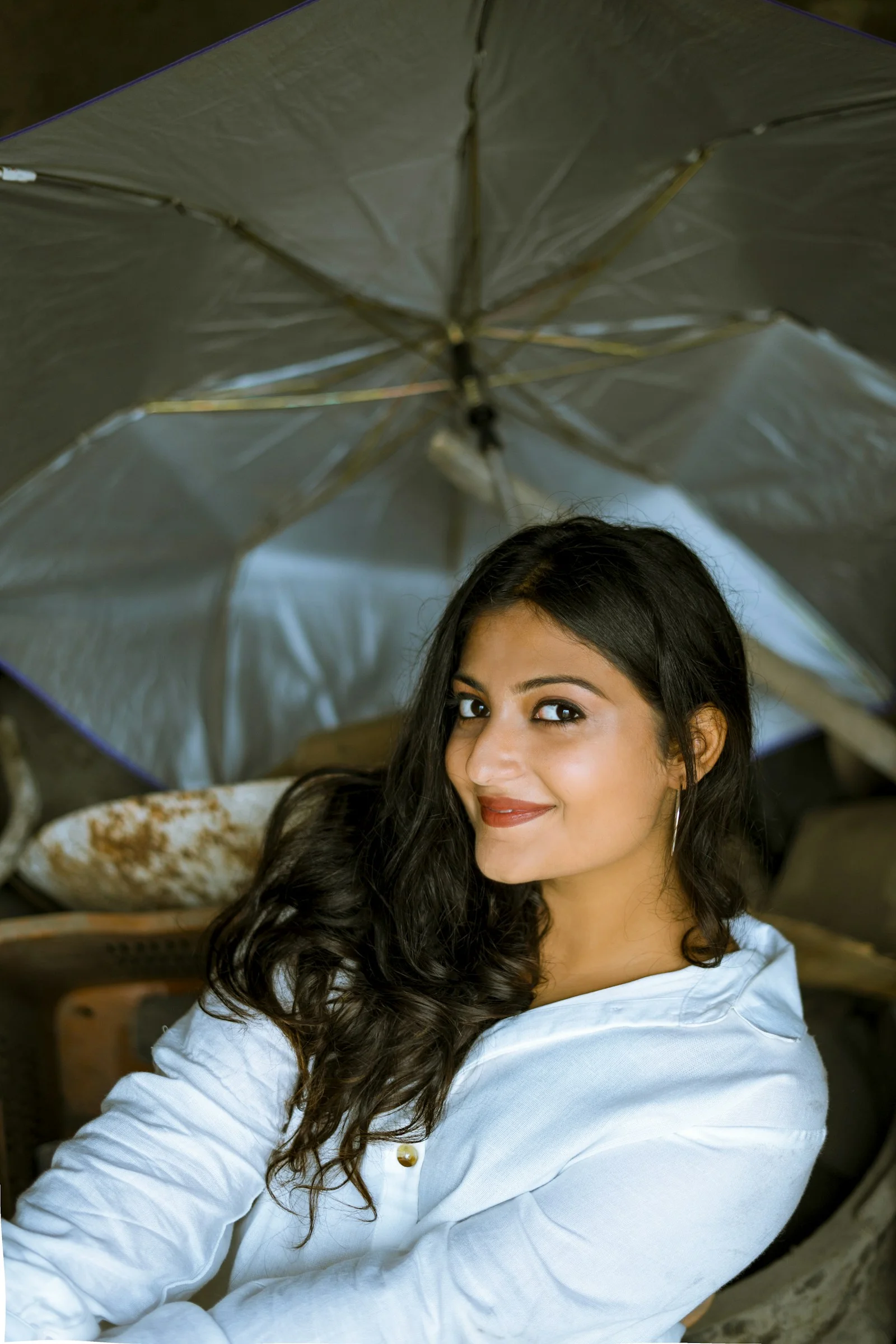 a woman sitting in a chair under an umbrella
