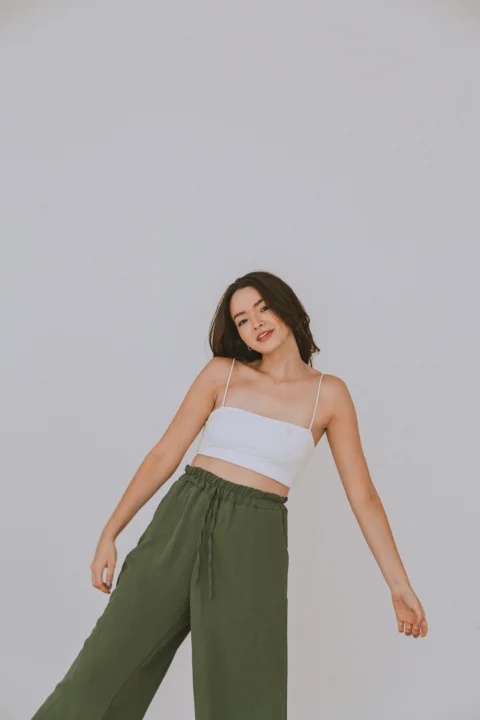 a woman in a white top and green pants