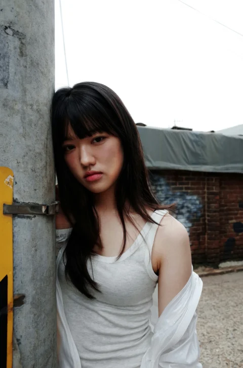 身穿白衬衫倚靠在柱子上的女子
